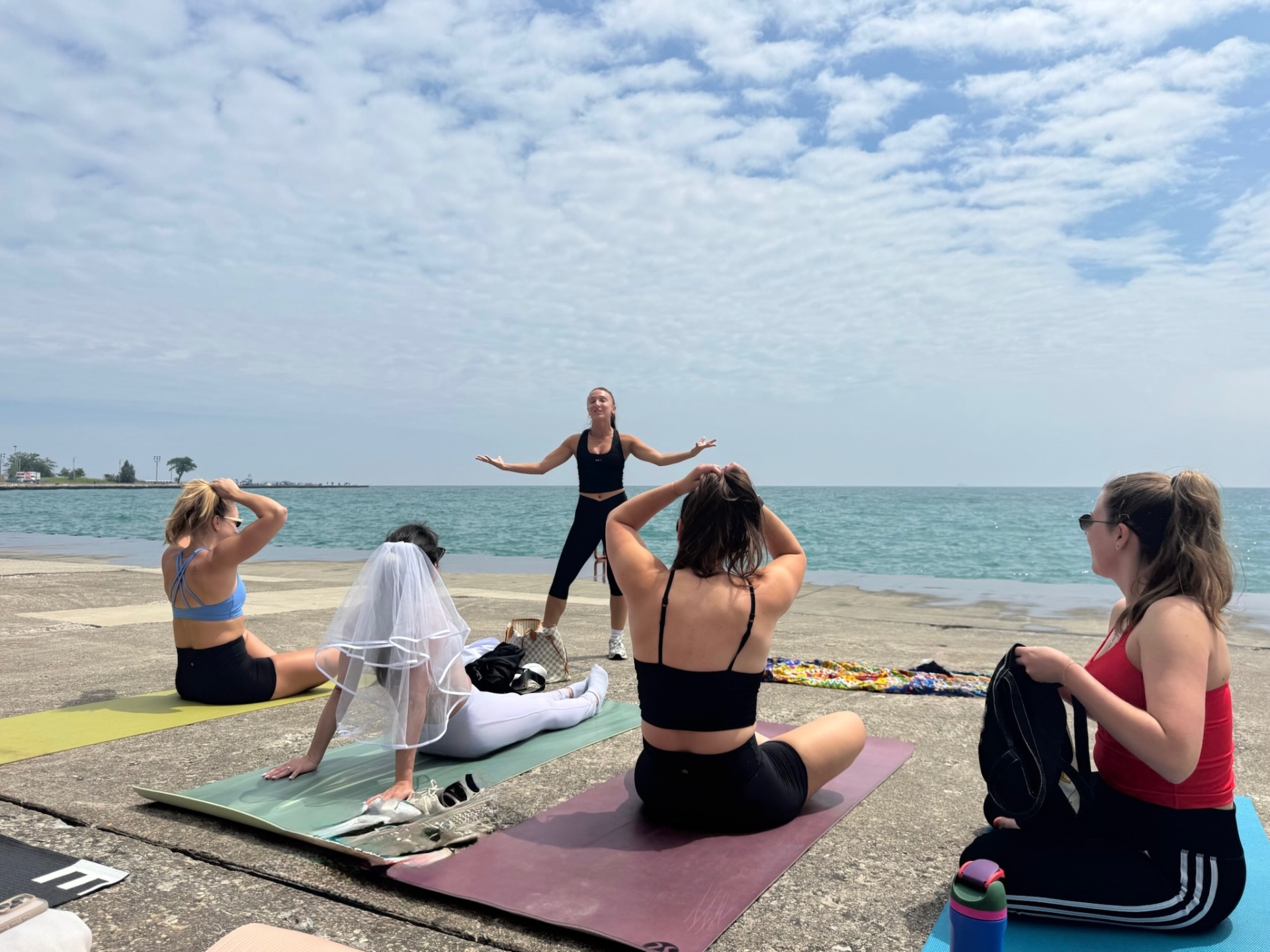Michelina leading a waterfront bridal movement experience as a guest wears a veil